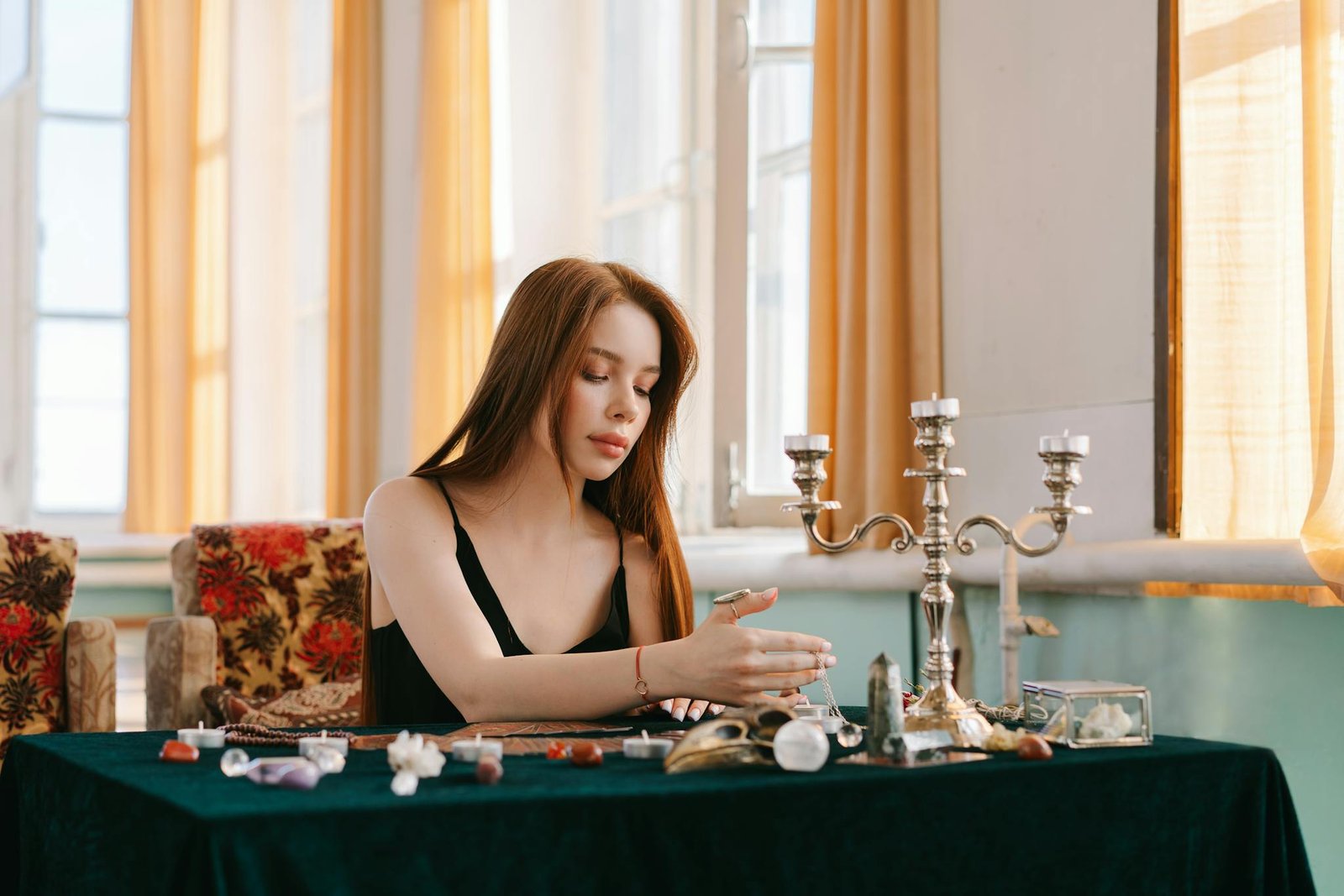A young woman meditates with crystals and spiritual items in a serene indoor setting.